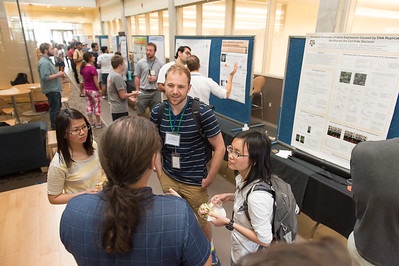 Students share research at a poster presentation.